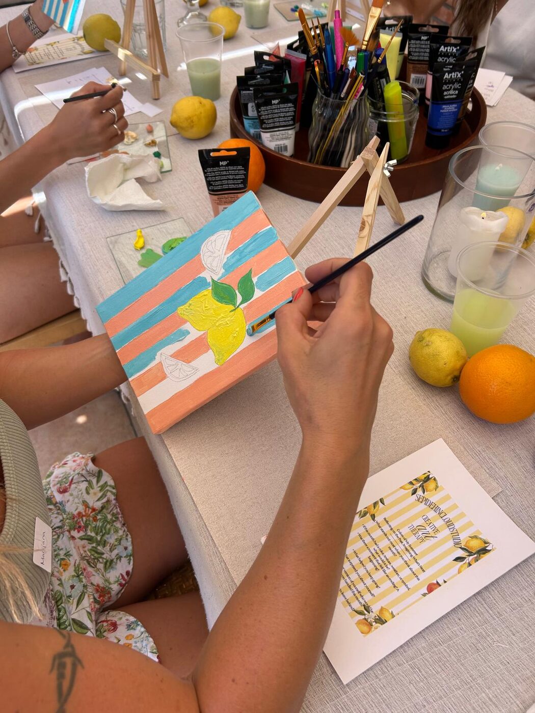 Hands painting a bright lemon still-life