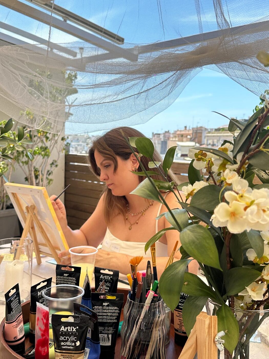 Painting at a sunlit rooftop table with flowers